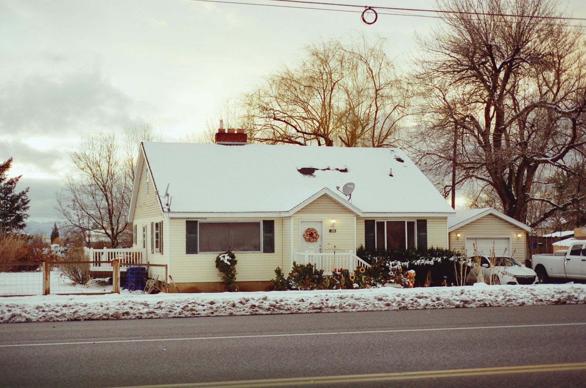 Postwar cape house with a brick chimney and a snow-covered roof